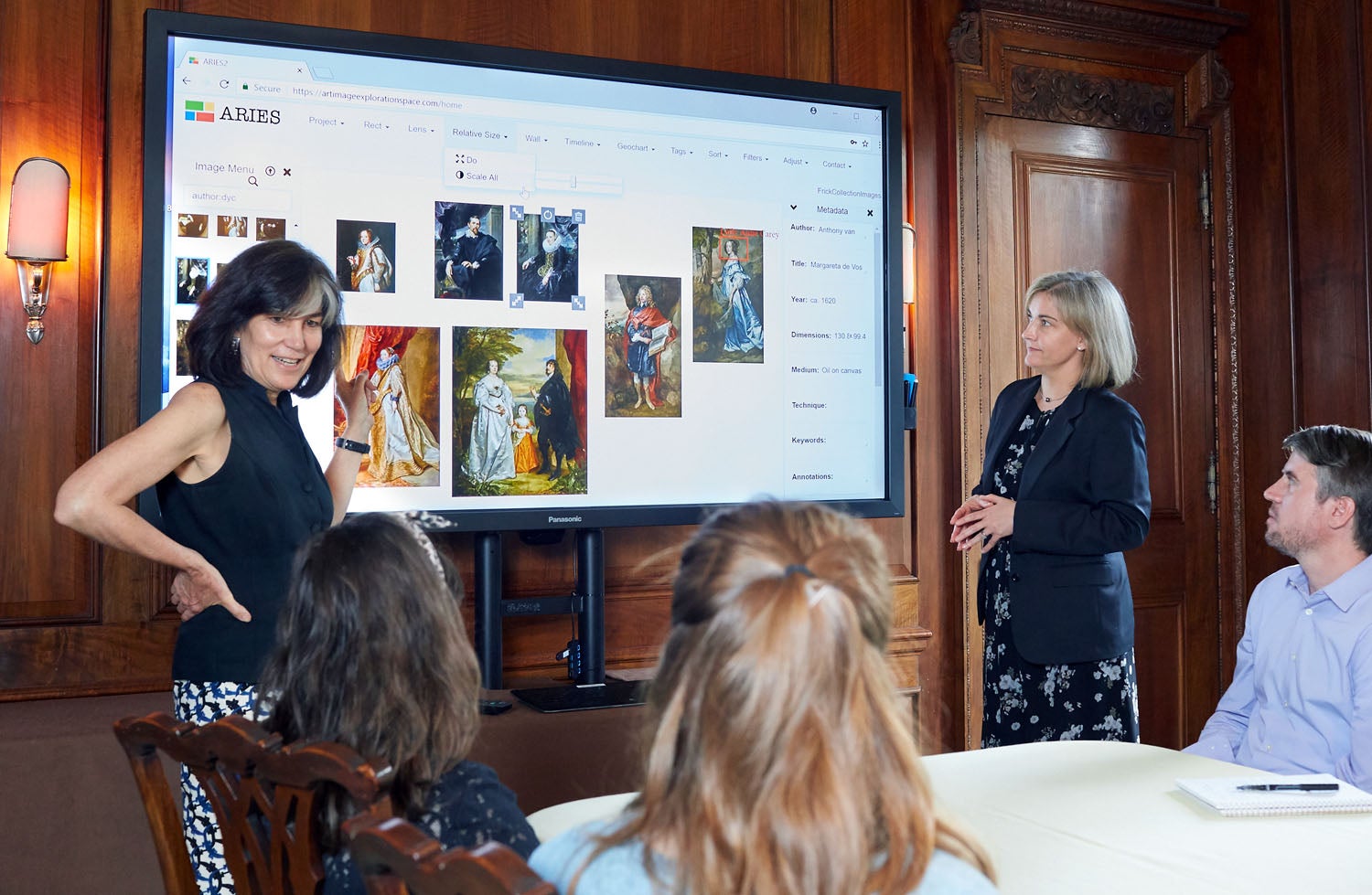 Two women in front of a screen demonstrate how to use a tool for digital image organization and manipulation.