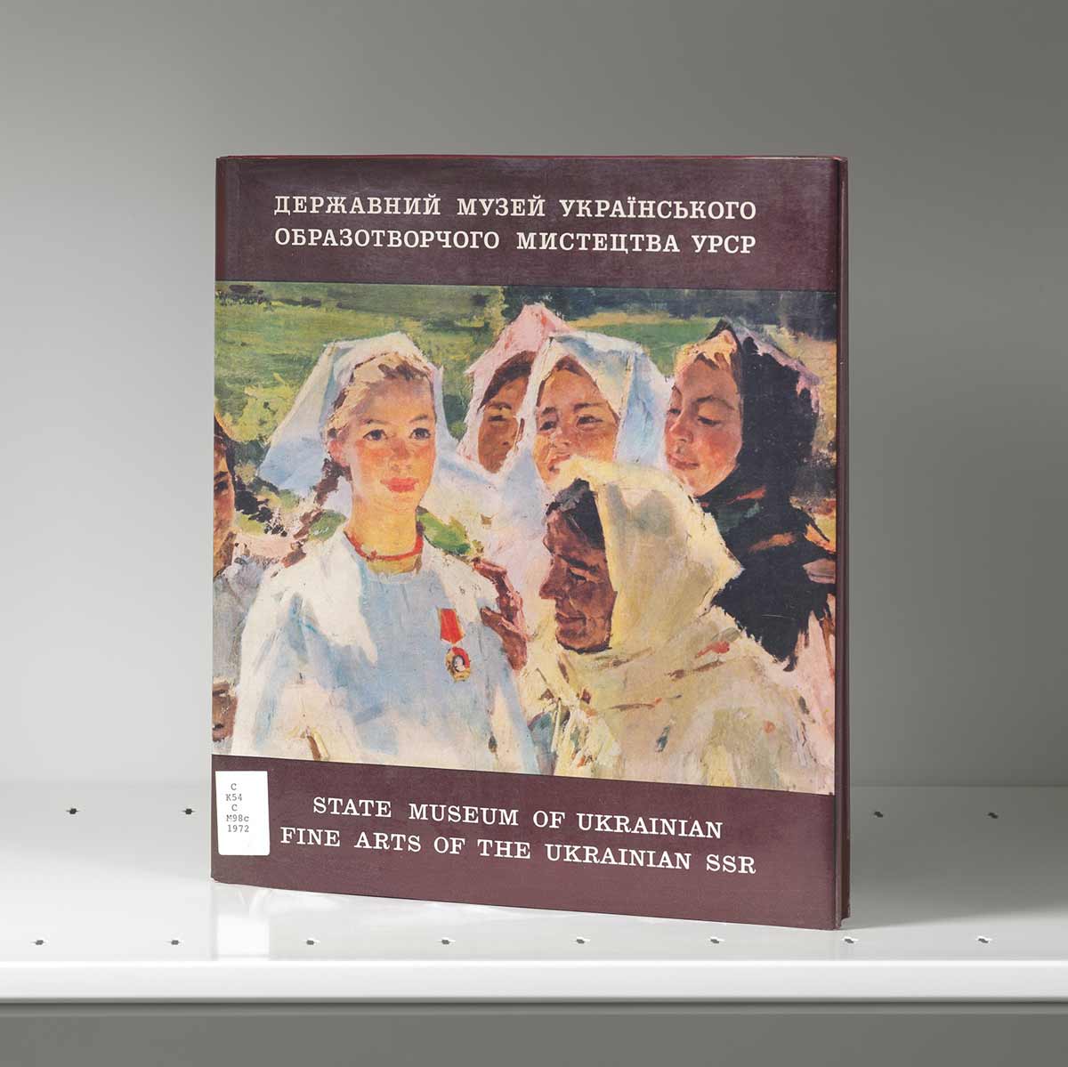 Book on a shelf whose cover features an artwork of young women in black and white headscarves