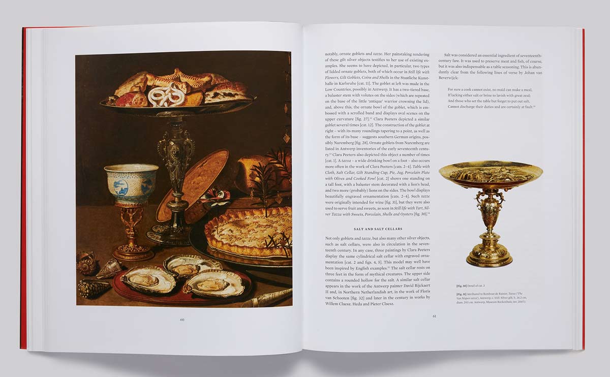 Book spread featuring a painting of a lavish table spread and an image of a gold tazza