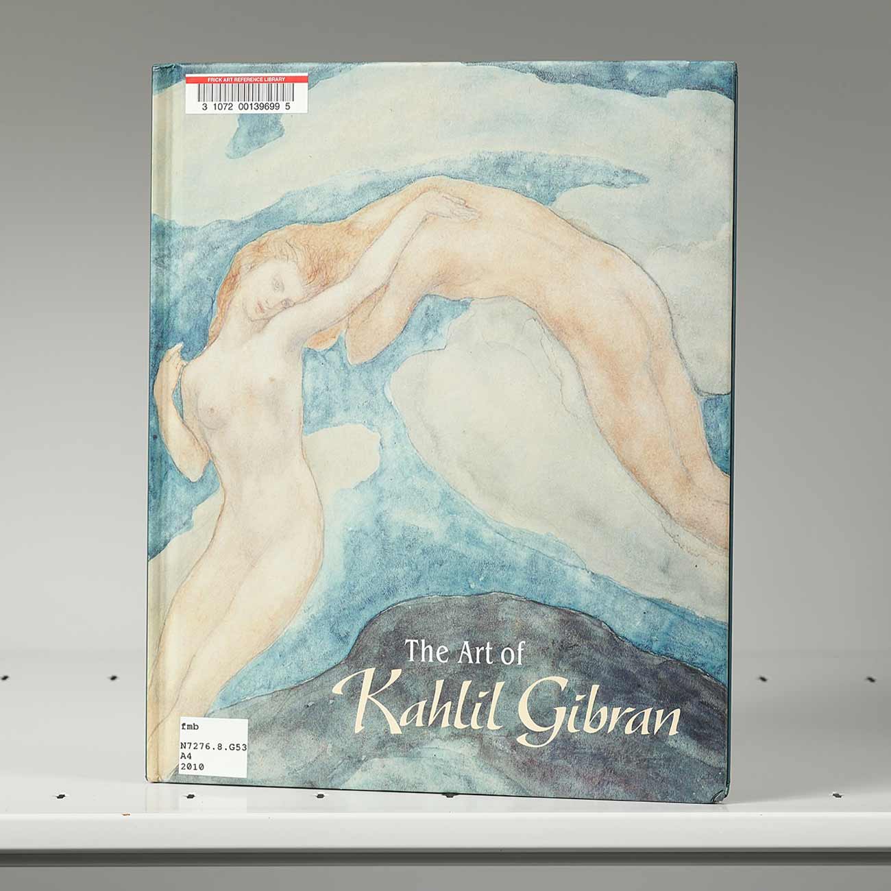 Book on a shelf whose cover features an artwork of two nude female figures floating through the air