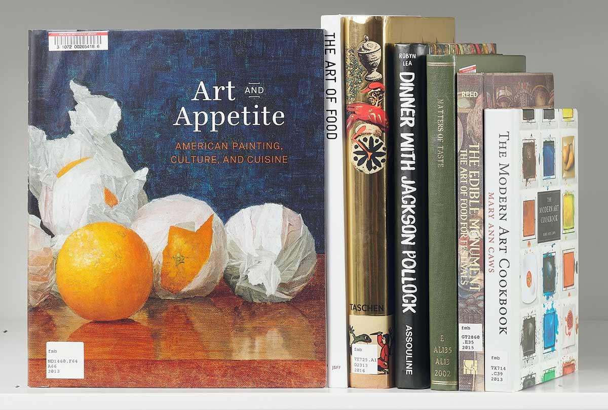 Stack of books next to a book whose cover features an artwork of oranges