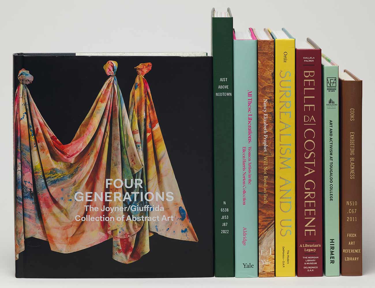 Stack of books next to a book cover featuring a colorfully painted draped canvas