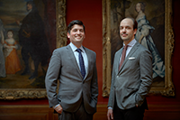 two male curators standing in front of paintings in the Oval Gallery