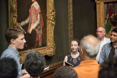 group in gallery surrounding painting