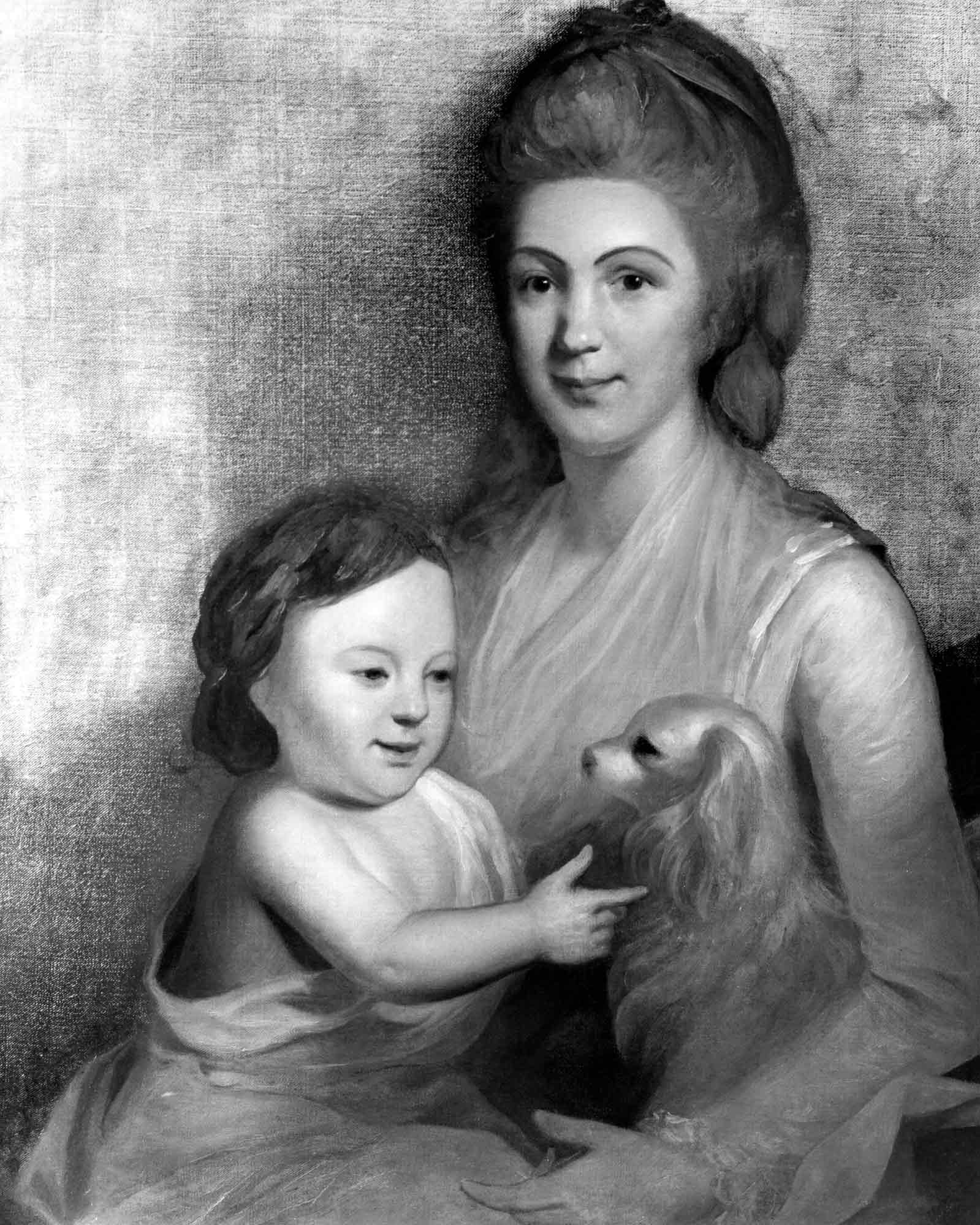 A woman holding a young child and a small spaniel in her lap.