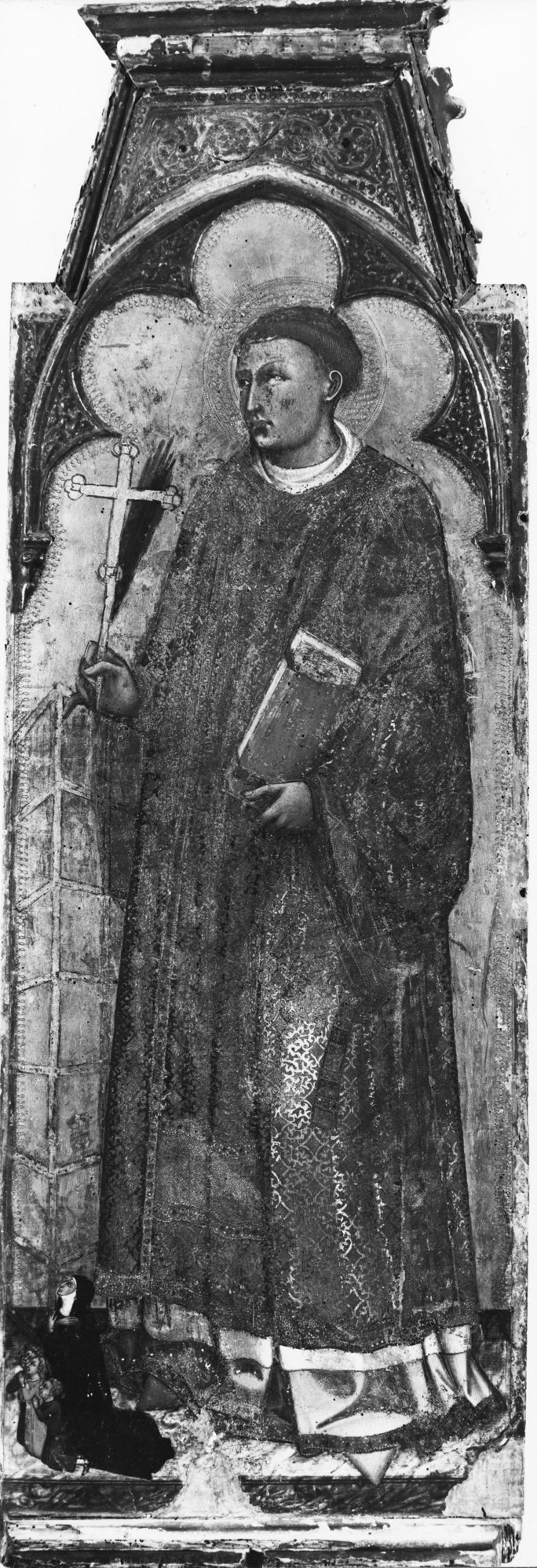 Standing young male saint in a panel holding a cross and a book and facing left.