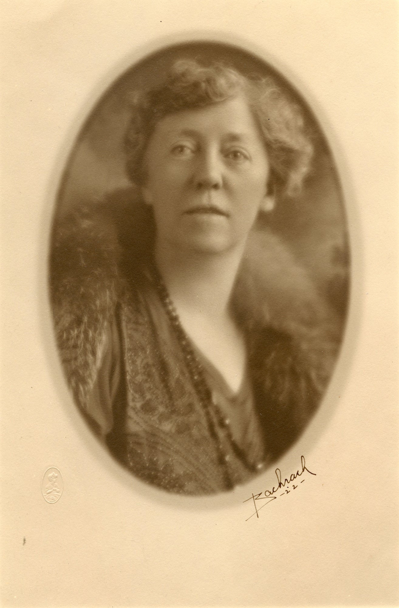 photo of Minerva Stone, with short hair, wearing long necklace and fur collar