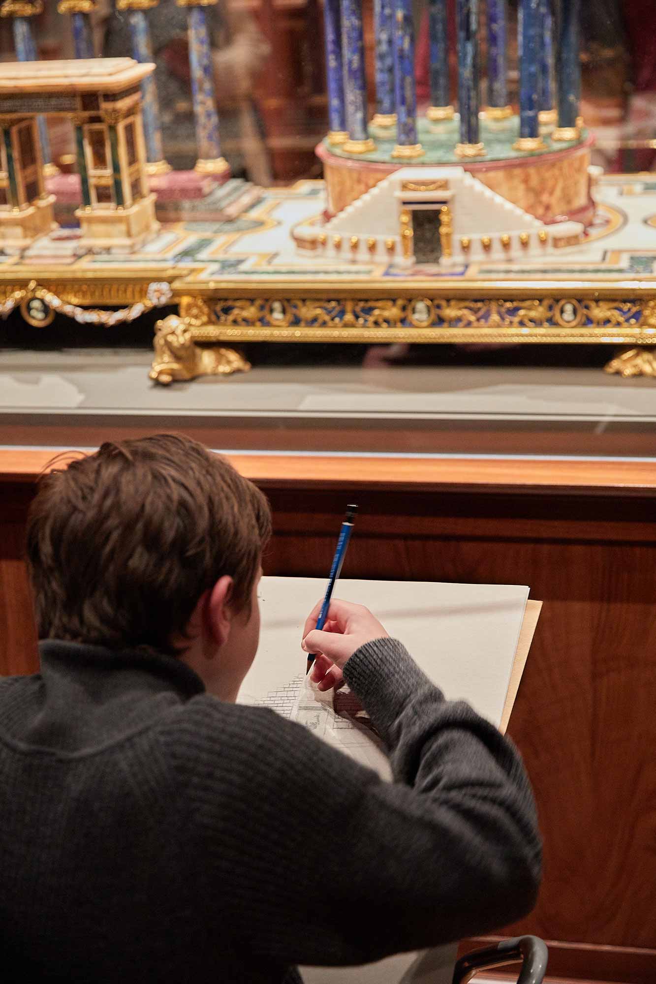 young man sketching in front of small sculpture in The Frick Collection gallery