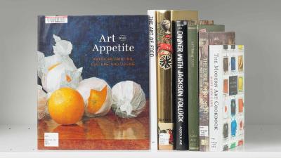 Stack of books next to a book whose cover features an artwork of oranges