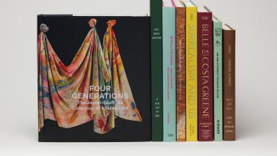 Stack of books next to a book cover featuring a colorfully painted draped canvas