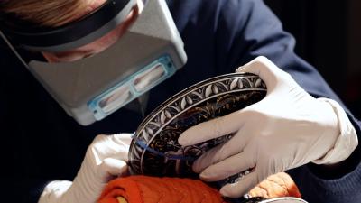 video still of conservator working on object