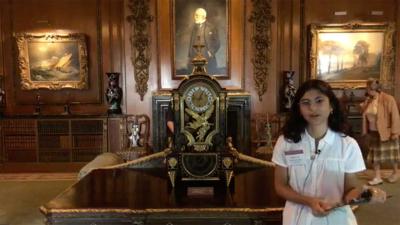 video still of young woman talking in front of clock