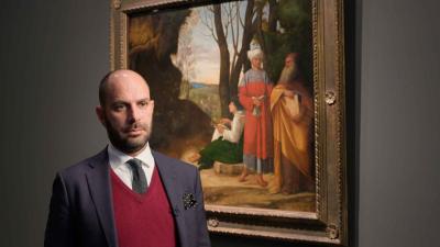 video still of Xavier Salomon standing in front of painting of three men