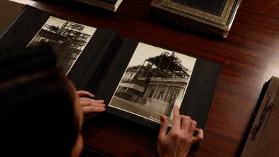 video still of woman looking over archival image