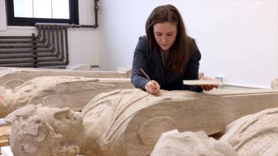 video still of woman working over caryatids, pillars in the shape of human figures