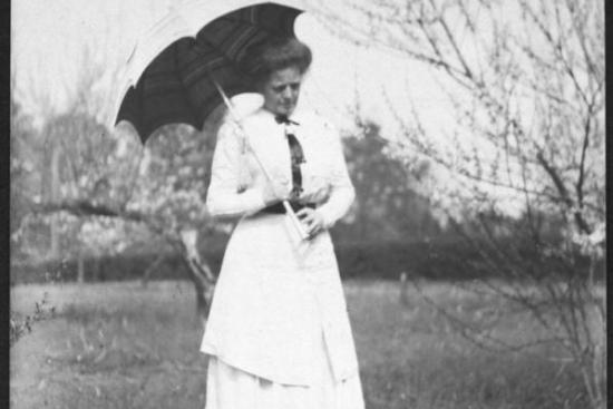 Black and white image of Adelaide Frick in a white dress holding a parasol