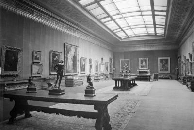 photo of gallery with paintings, sculptures on tables, and skylight, circa 1927 
