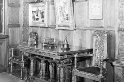 photo of wall in gallery with paintings and and chairs and table, circa 1955