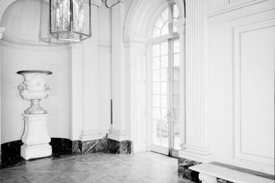 photo of hall with wood floor, chandelier, and large glass door and bench, circa 1977