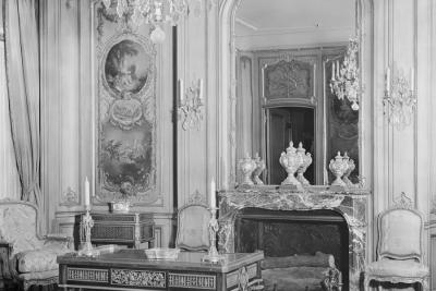 archival photo of room including desk, chandelier, mirror over fireplace