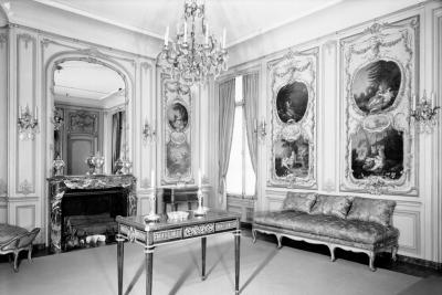 photo of room with paintings in panels, couch, chandelier, table, fireplace, circa 1953