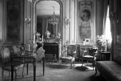 photo of room with desk, chairs, fireplace, large mirror, circa 1927