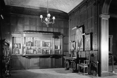 glass case with enamels and paintings in gallery room with paintings and sculptures on table, circa 1935