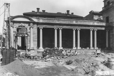 photo of portico or stone porch with columns under construction with workers seated, circa 1913
