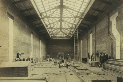 photo of of room under construction, with lumber, ladder to skylight, circa 1913