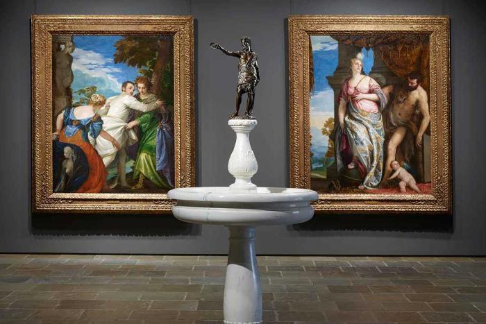 statuette situated between two larger paintings in gallery