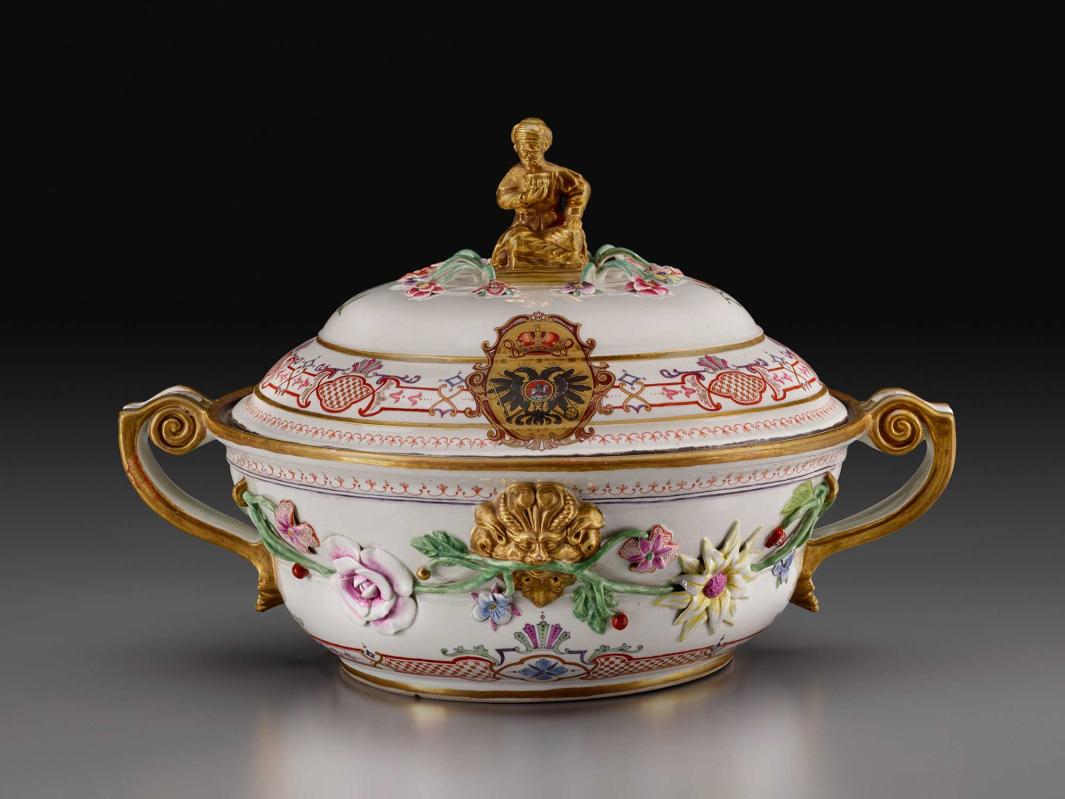 colorful porcelain deep covered dish with handles, decorated with flowers and figurine at top