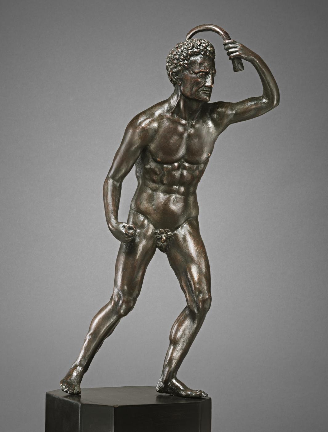 Bronze sculpture of a man holding a scraper above his head.