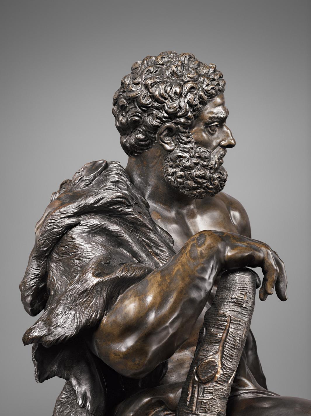 Bronze sculpture of seated male figure with a club, side view