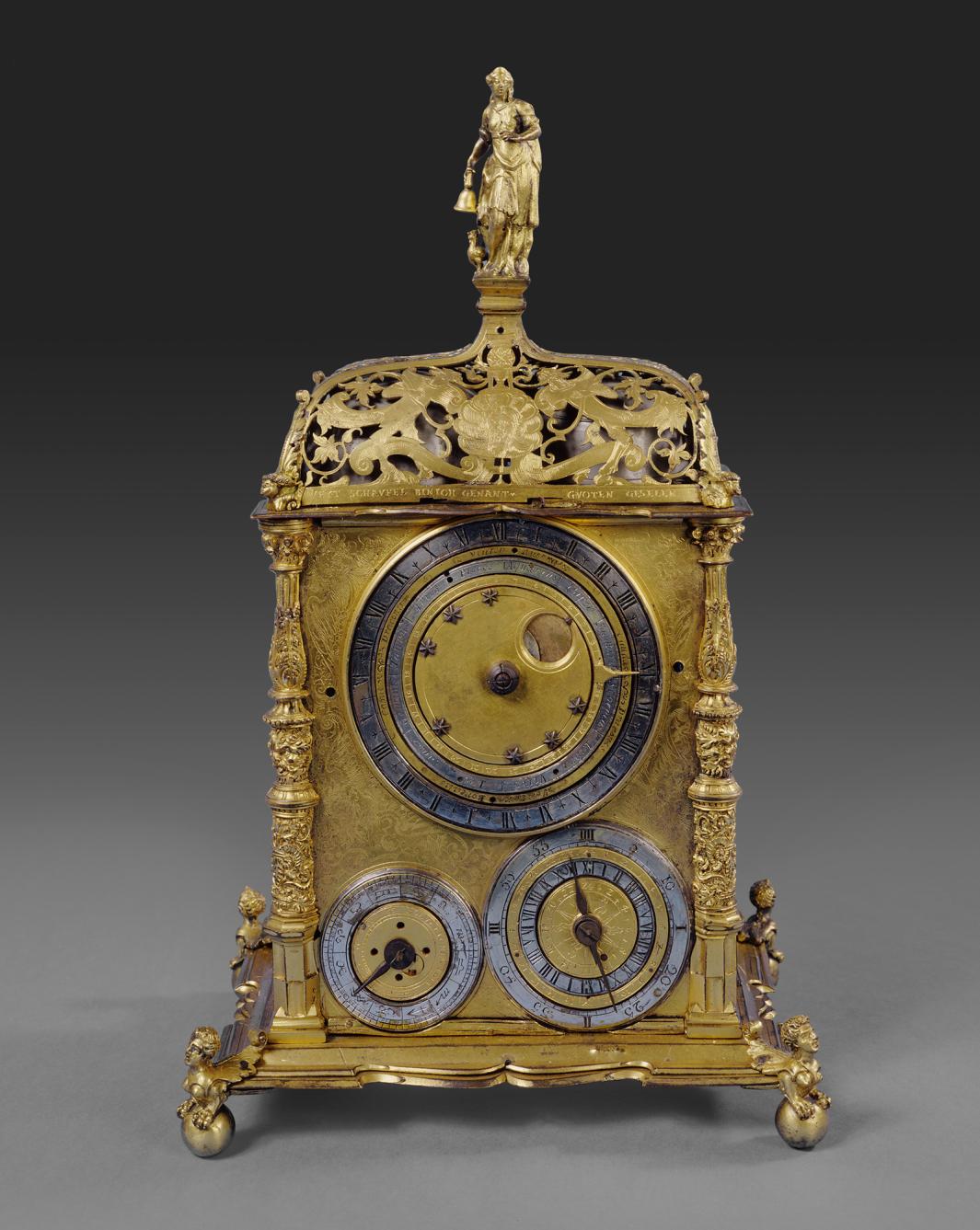 ornate gilt-brass table clock with astronomical and calendrical dials, with woman holding bell at top