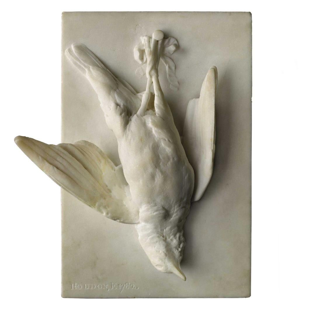 Marble sculpture in high-relief of a dead songbird hanging upside down, pinned by its legs.