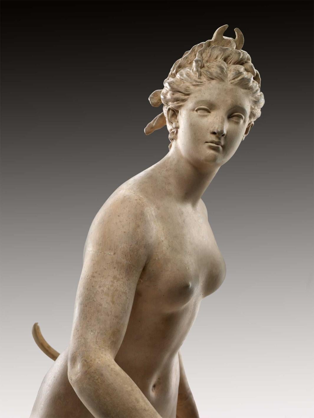 Close-up view of a terracotta sculpture of the nude goddess Diana holding a bow and on one foot