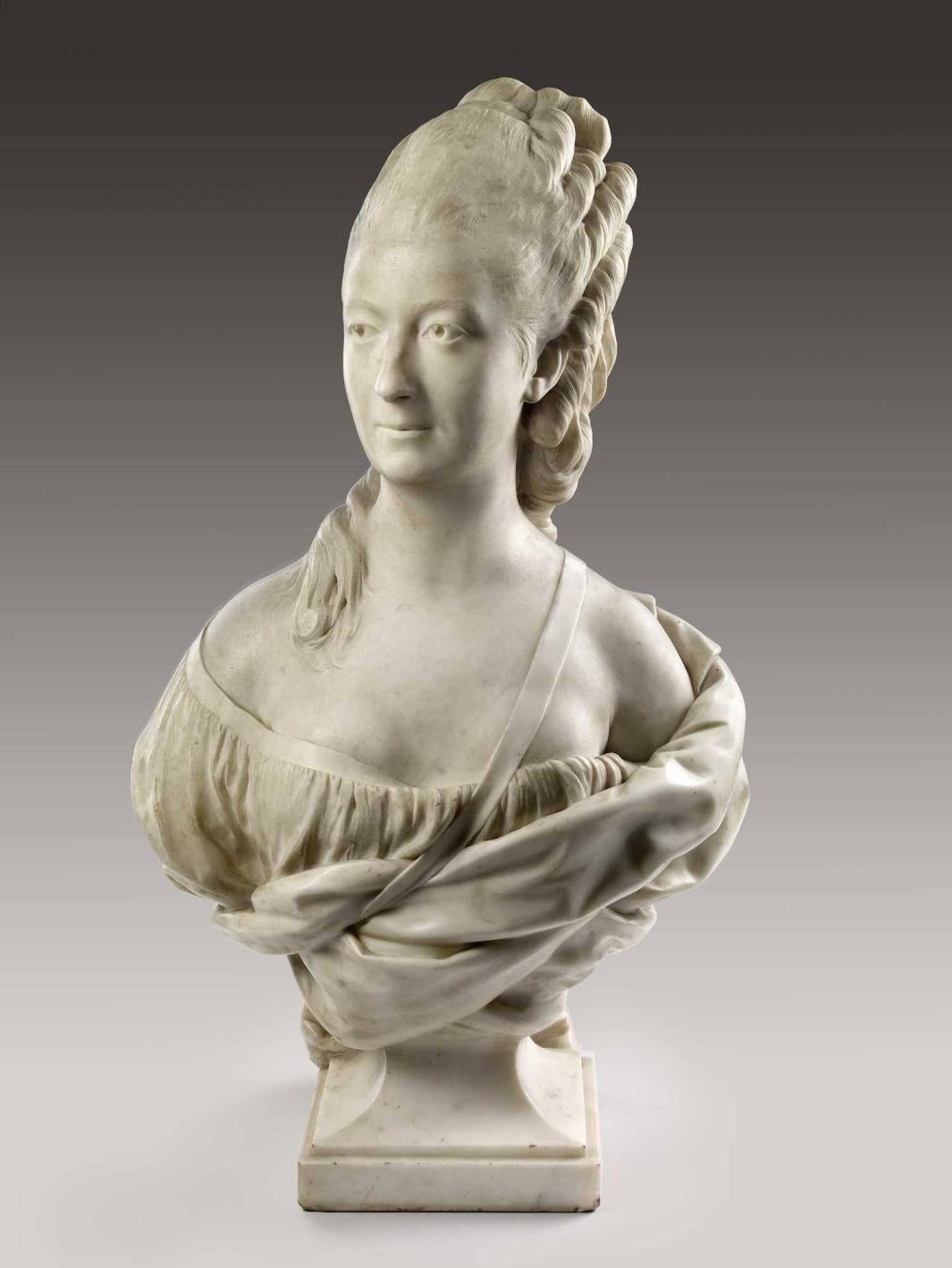 Alternate view of a marble bust of a woman draped in a garment with long, curly hair.