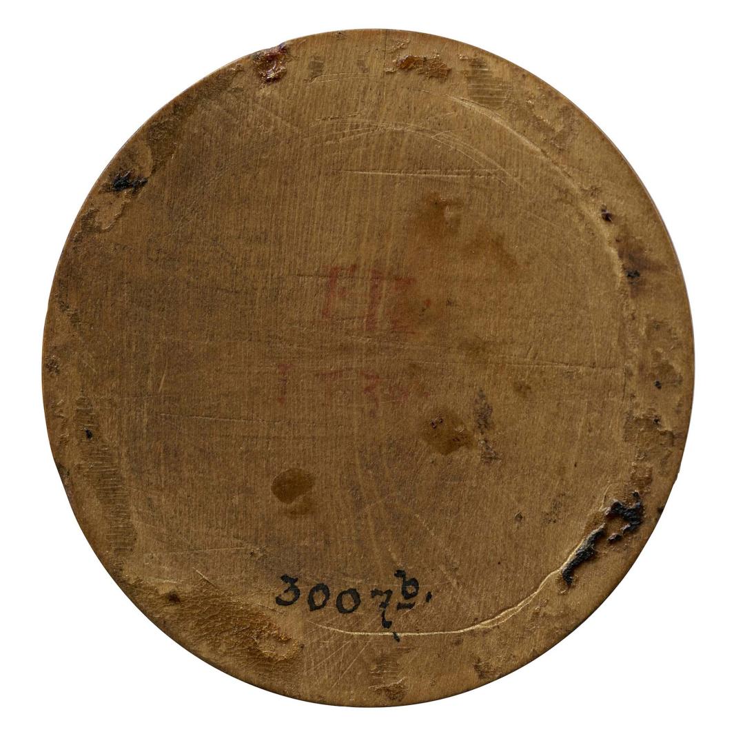 Wooden medal with the number 3007b written in ink