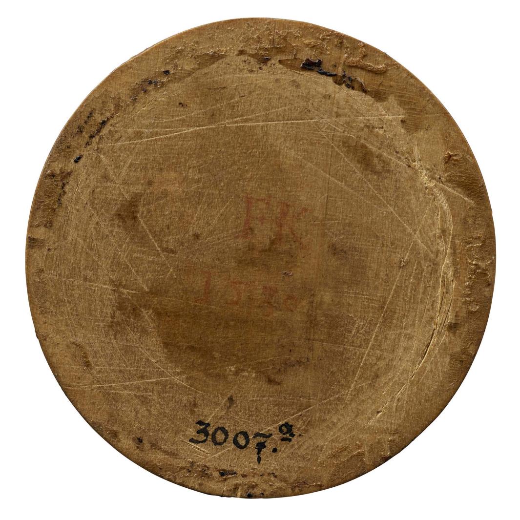 Wooden medal with the number 3007a written in ink