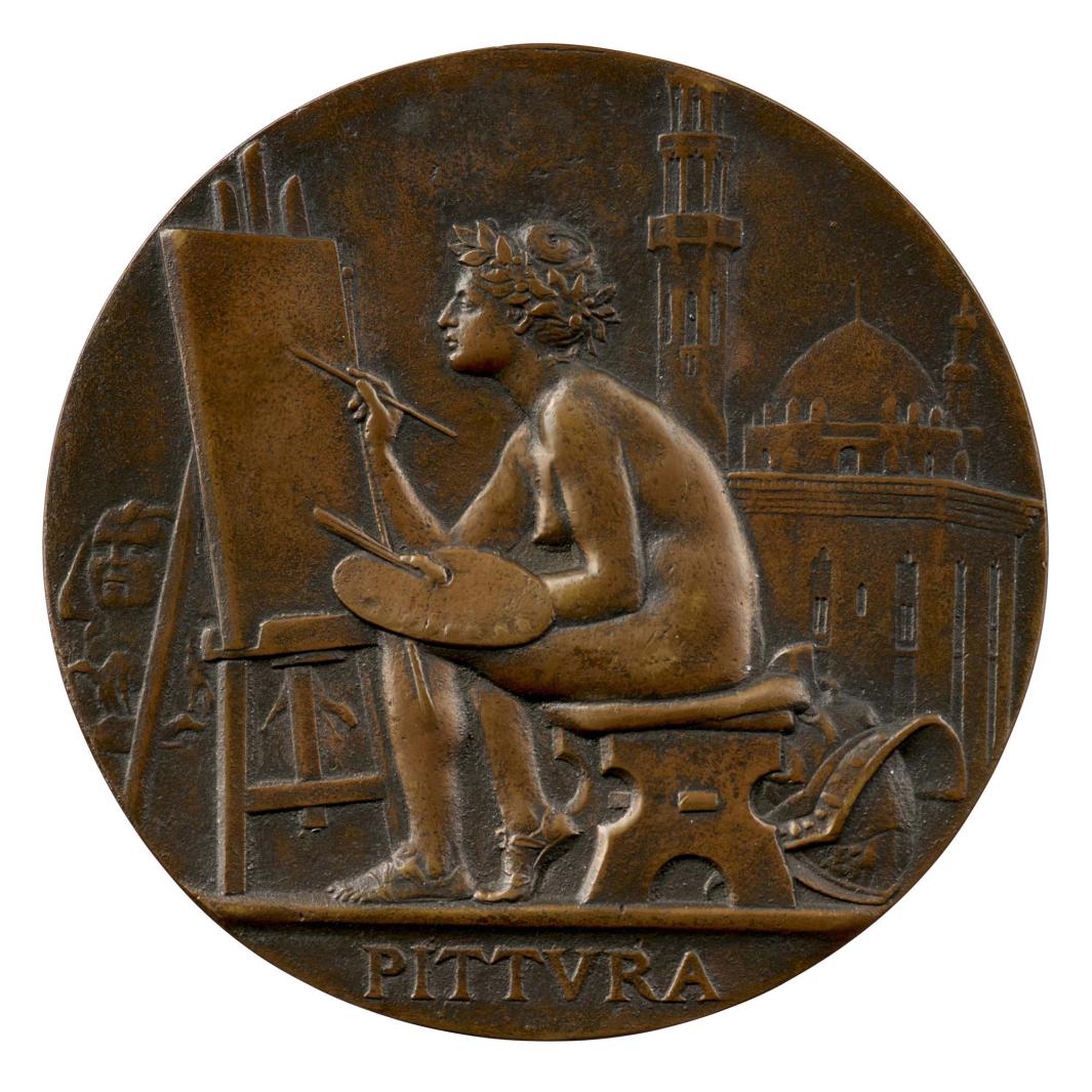Bronze medal of a nude woman seated on a bench in front of an easel, holding a paintbrush in her right hand and a palette in her left hand, in profile to the left, with a city in the background 