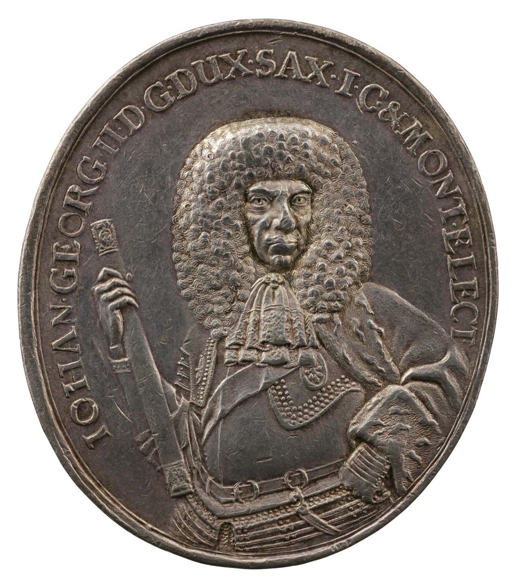 Silver medal of a man wearing armor and holding a baton 