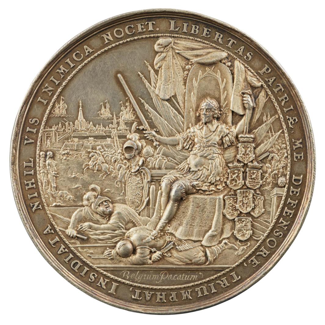 Silver medal of a man sitting upon a throne wearing classical armor and holding a sword in his right hand 