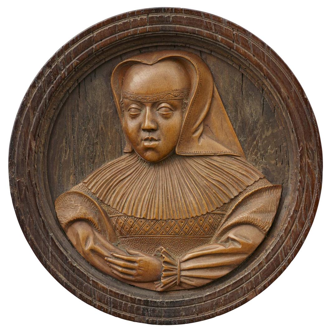 Wood medal in a wood frame of a woman with crossed arms wearing a widow dress
