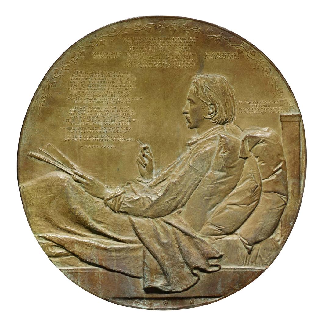 Bronze medal of a man reclining in bed against pillows and with a blanket on his lap, sheets of paper in his left hand and a cigarette in his right