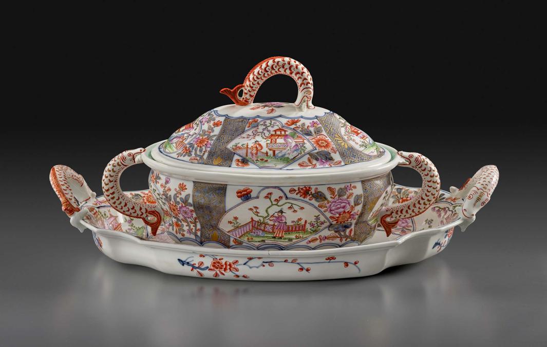 porcelain tureen and stand colorfully decorated with various scenes and eels or fish as handles