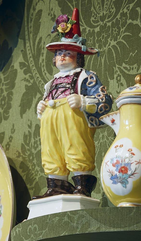 colorful porcelain male figure wearing hat with flowers and yellow pants
