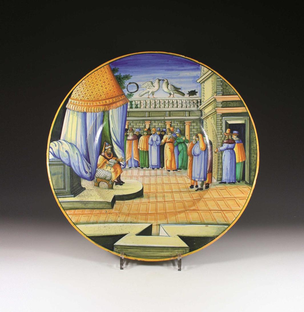 Earthenware plate with a scene of a seated figure in a courtyard, under a canopy, talking to a standing group of people.