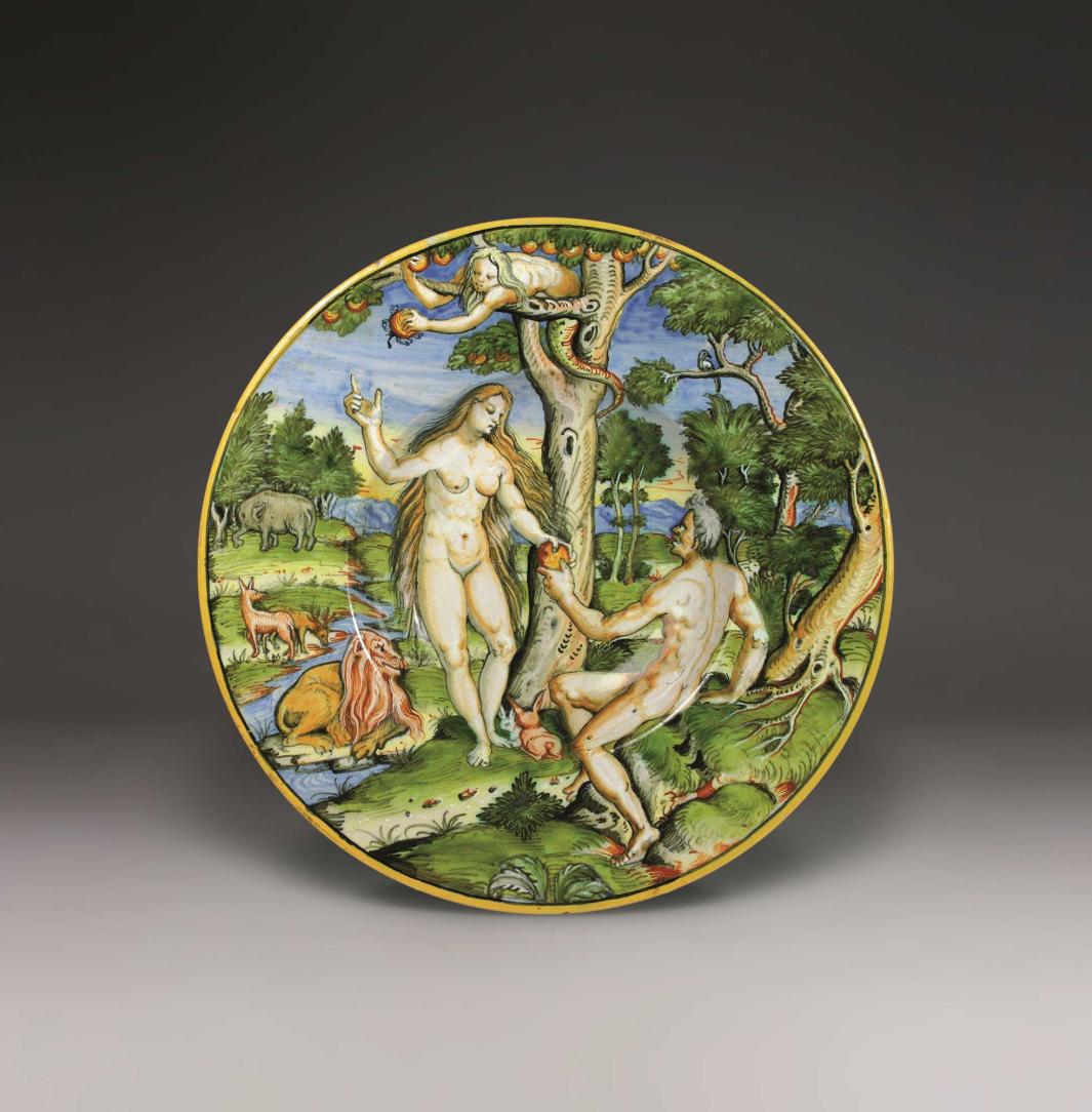 Earthenware plate with a landscape scene of various animals and two nude figures at the center exchanging a piece of fruit from the tree they are under.