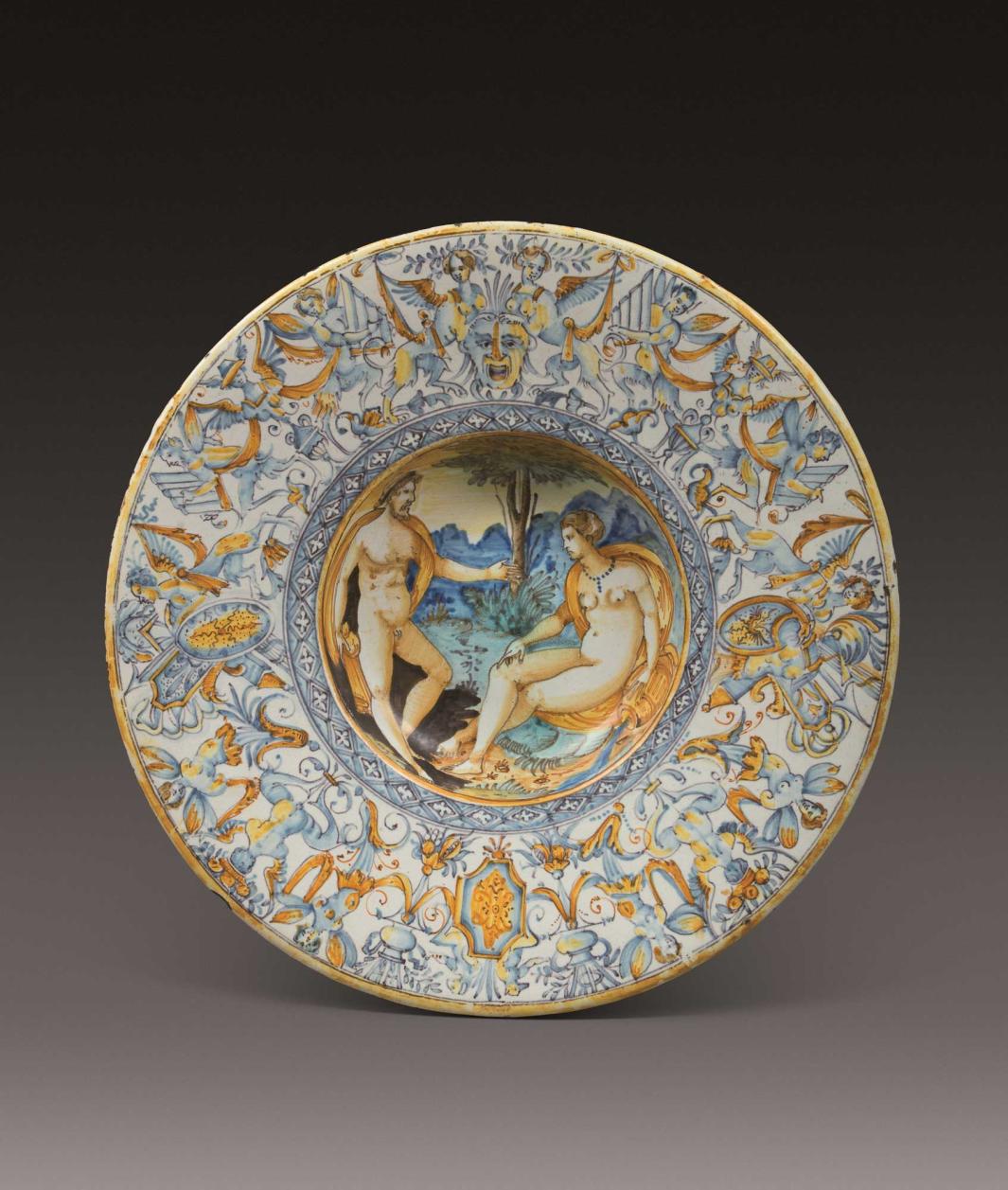 Earthenware plate with two nude figures talking in the center, surrounded by a design of half-human, half-animal figures on the outside. 