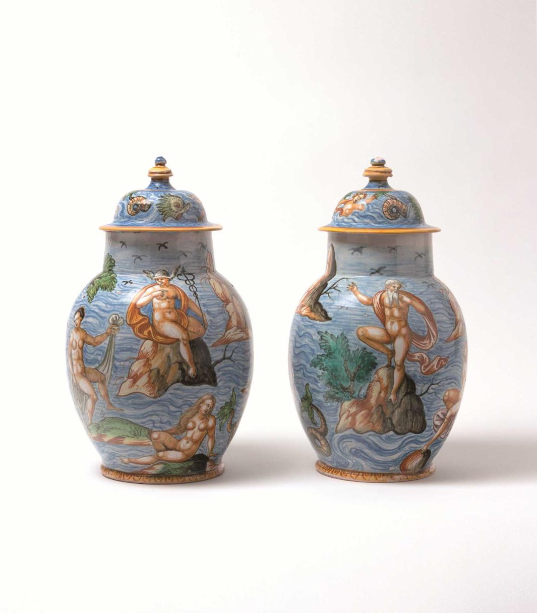 Two earthenware vases with seascape scenes of nude figures sitting on rocks and sea creatures in the water.